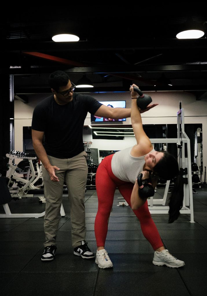 Personal trainer coaching client with kettlebell at gym